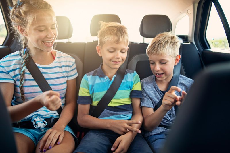 Three children playing games in the car