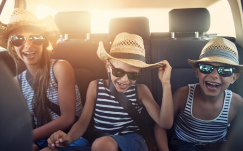 Three children laughing on road trip