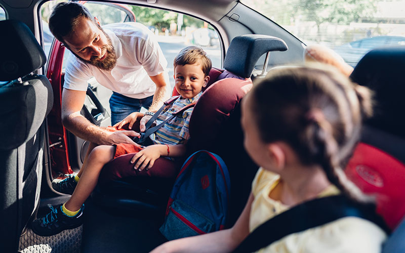 Father Buckling Kids into Family Car
