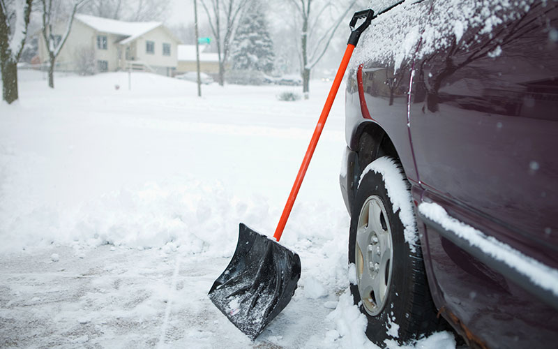 Snow shovel leaning on a car