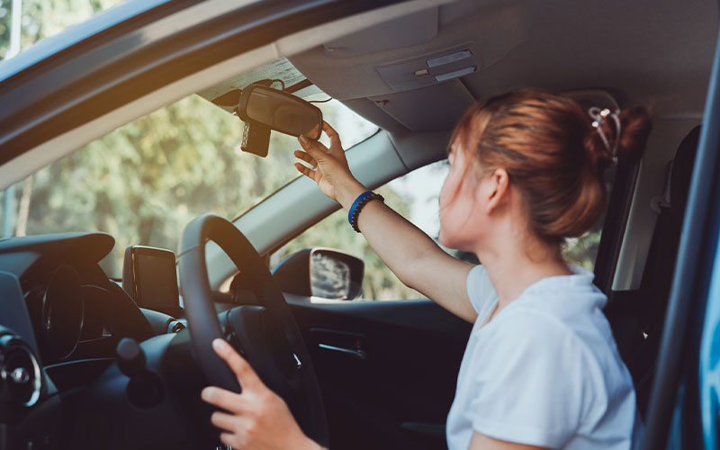 Driver adjusting rearview mirror