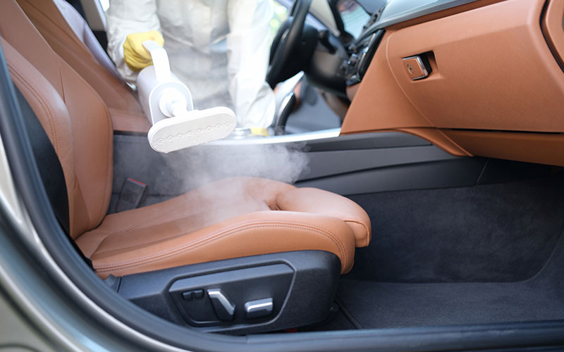 Person steam cleaning their car interior Person steam cleaning their car interior