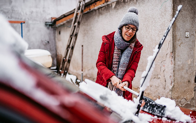 Woman cleaning snow off her car Woman cleaning snow off her car