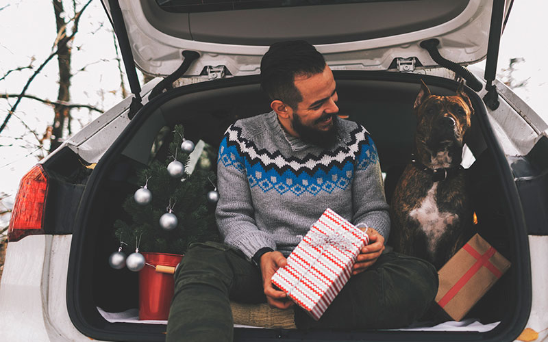 Guy with his dog and gifts in the car