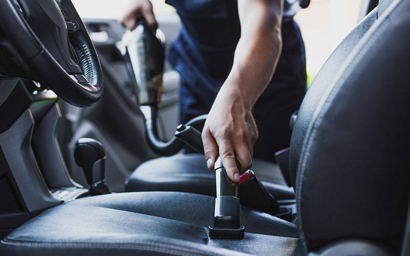 Person vacuuming their car Person vacuuming their car