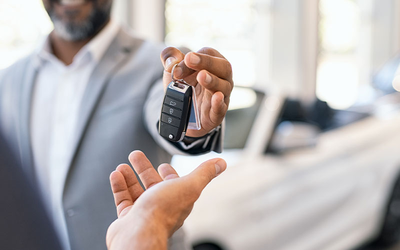 Salesman giving new car keys to customer
