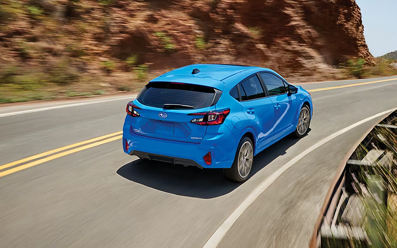 a blue 2025 Subaru Impreza driving away from the camera