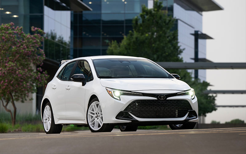 White Corolla hatchback in a city.