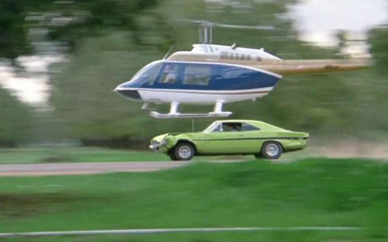 A greenish-yellow 1973 Pontiac Ventura behind a helicopter during a car chase in the movie "Dirty Mary, Crazy Larry"