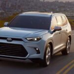 A white 2026 Toyota Grand Highlander driving down a highway