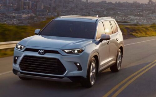 A white 2026 Toyota Grand Highlander driving down a highway