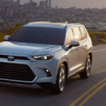 A white 2026 Toyota Grand Highlander driving down a highway