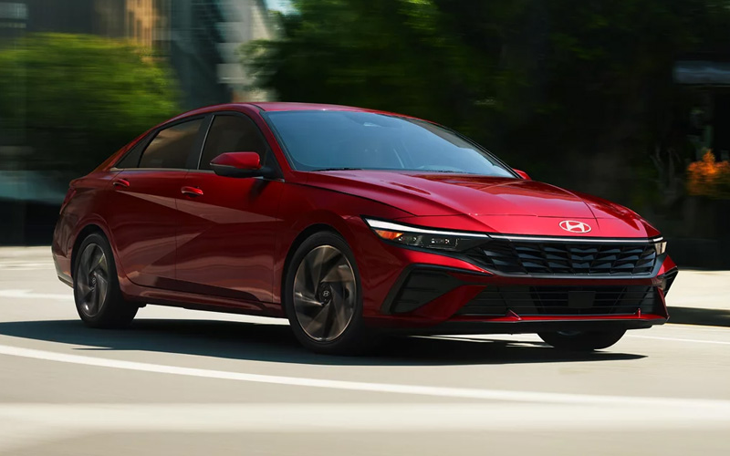 A red 2026 Hyundai Elantra in traffic on a city street.