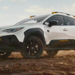A white 2026 Subaru Crosstrek hybrid parked on a dirt road in the middle of nowhere