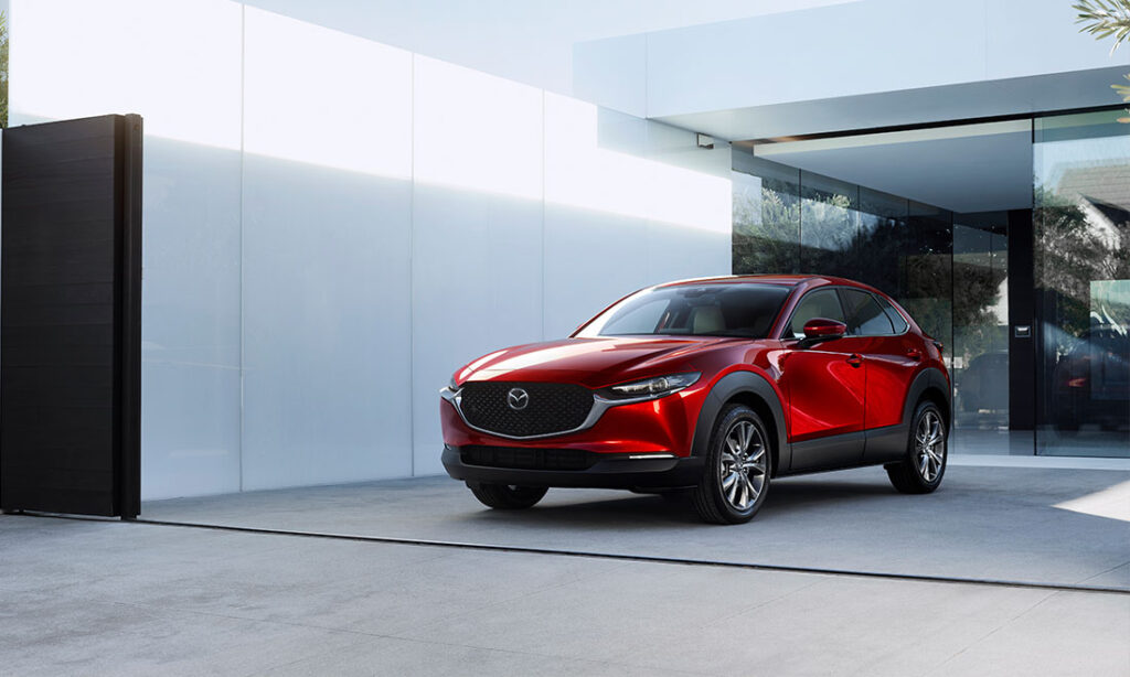 Red Mazda CX-30 parked next to a house.