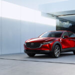 Red Mazda CX-30 parked next to a house.