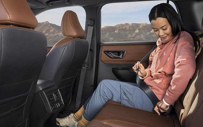 A woman buckling her seatbelt in the second row of a 2026 Subaru Outback