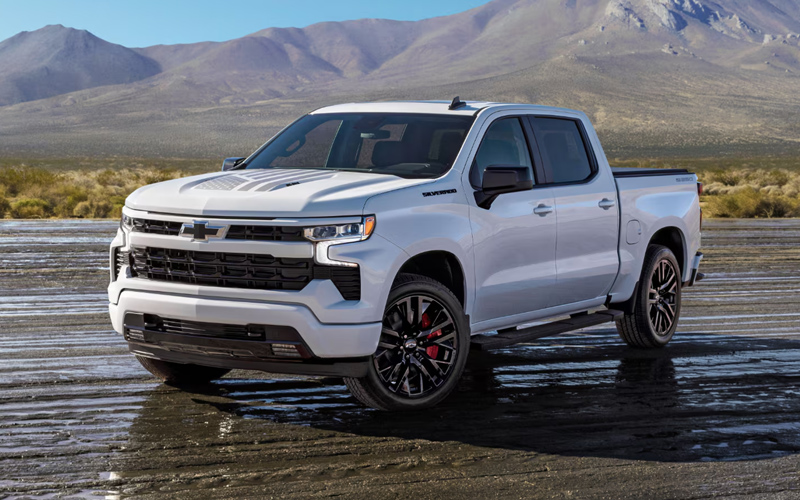 A white 2026 Chevy Silverado 1500 parked on pavement with mountains in the background.