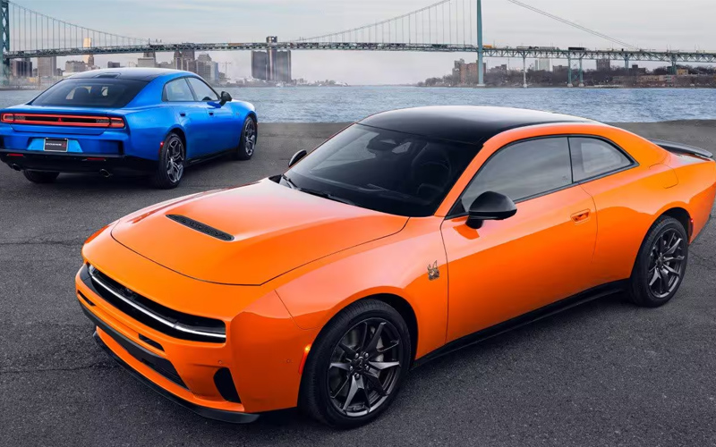 An orange 2026 Dodge Charge in the foreground of the photo and a blue 2026 Dodge charger in the background
