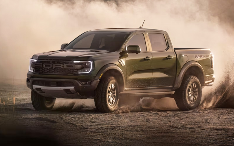 A black 2026 Ford Ranger kicking up dust in a rural area.