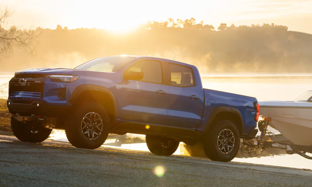 A blue 2026 Chevy Colorado towing a boat out of the lake on a boat ramp