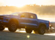 A blue 2026 Chevy Colorado towing a boat out of the lake on a boat ramp