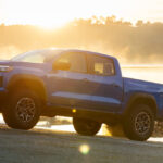 A blue 2026 Chevy Colorado towing a boat out of the lake on a boat ramp