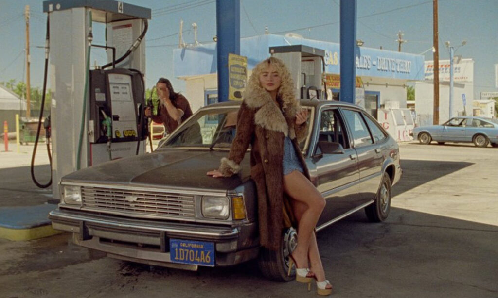 Sabrina Carpenter leaning against a 1984 Chevrolet Citation in the Manchild music video