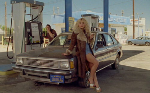 Sabrina Carpenter leaning against a 1984 Chevrolet Citation in the Manchild music video
