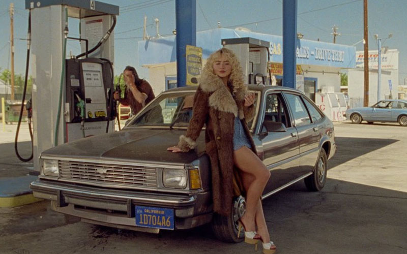 SC_1984_Chevrolet_Citation Sabrina Carpenter leaning against the hood of a 1984 Chevrolet Citation