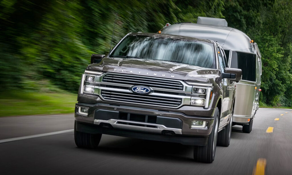A 2026 Ford F-150 hauling a trailer down a two-lane highway.