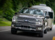 A 2026 Ford F-150 hauling a trailer down a two-lane highway.