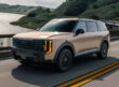 A tan 2027 Kia Telluride in motion on a two-way highway.