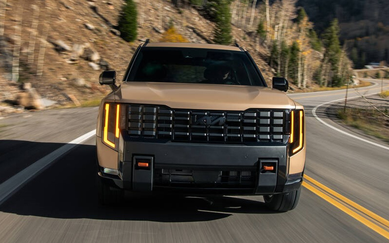 2027 Kia Telluride Powertrain A front view of a 2027 Kia Telluride in motion on a two-lane highway